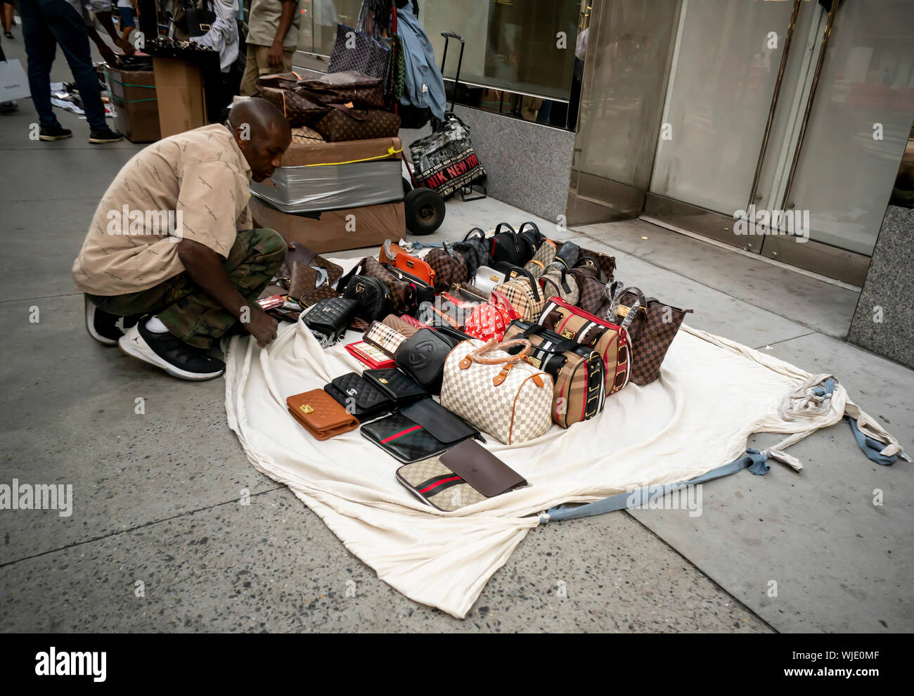 vendor illegally selling imitation name brand handbags on Canal Street  Manhattan New York Stock Photo - Alamy