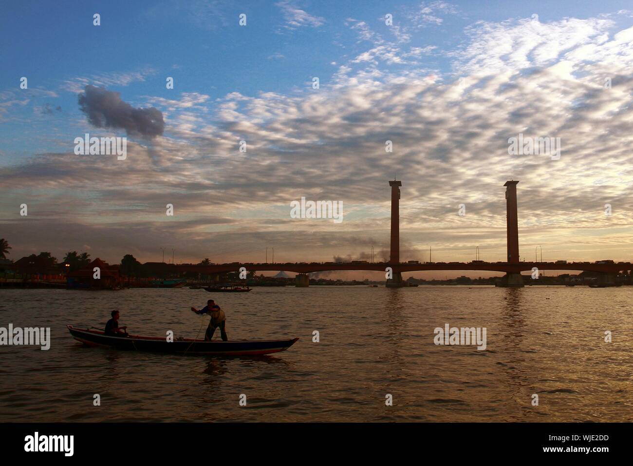 People On Boat At Musi River With Ampera Bridge In Background Stock Photo