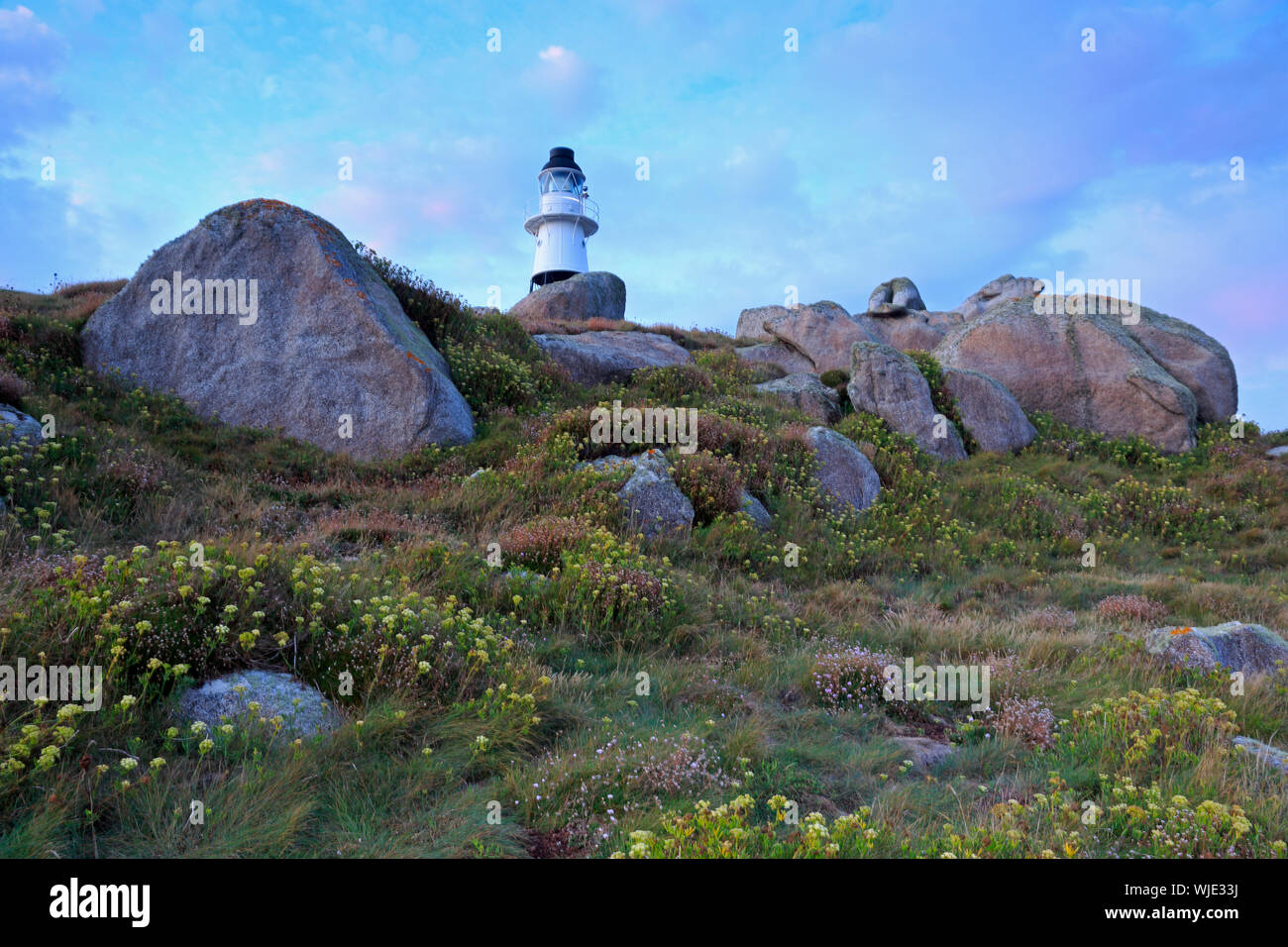 Granite blocks on Penninis Head St Mary's Scilly showing the Lighthouse Stock Photo