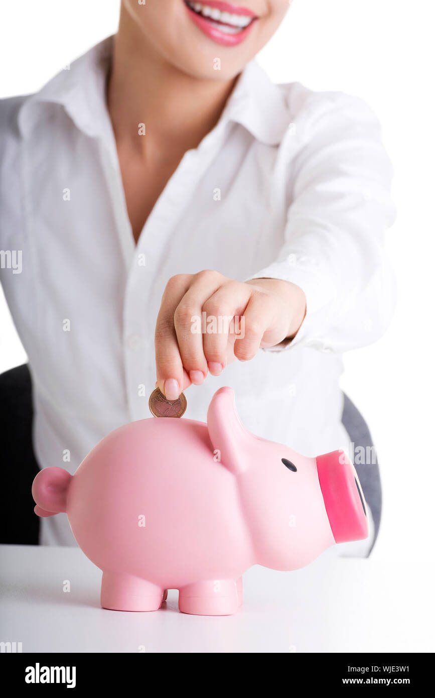 Happy businesswoman putting an euro coin into a piggy bank isolated on ...