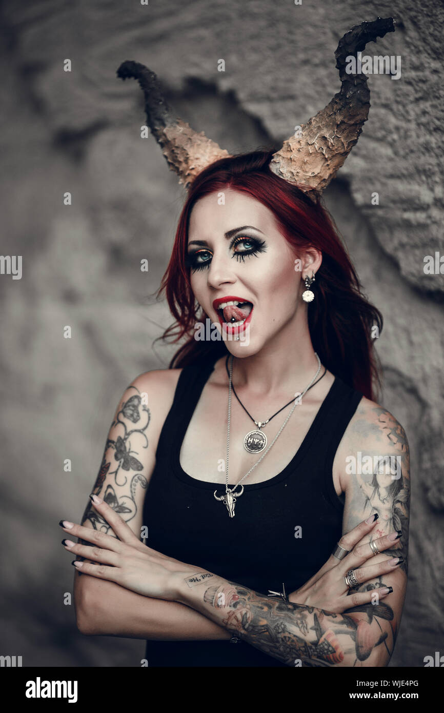 woman with red hair, huge devil horns decorates her head. Portrait of the beautiful young woman