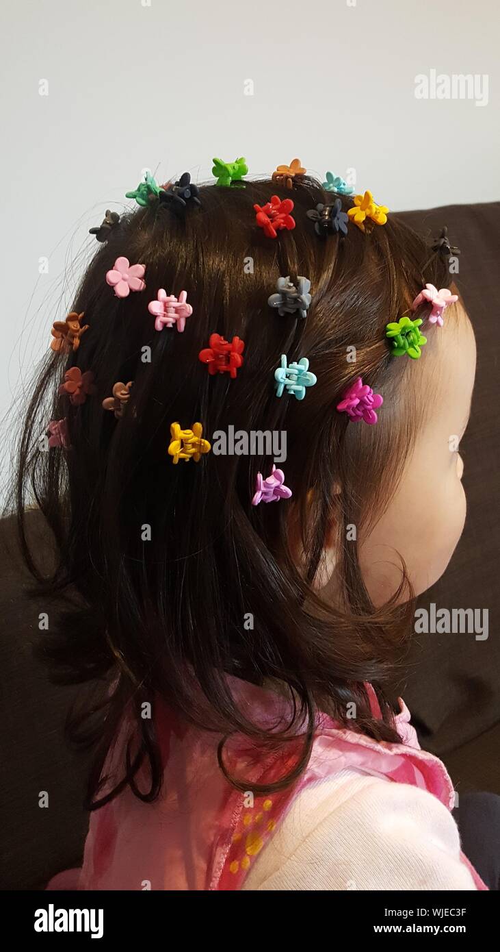 Side View Of Girl With Colorful Hair Clips Standing At Home Stock