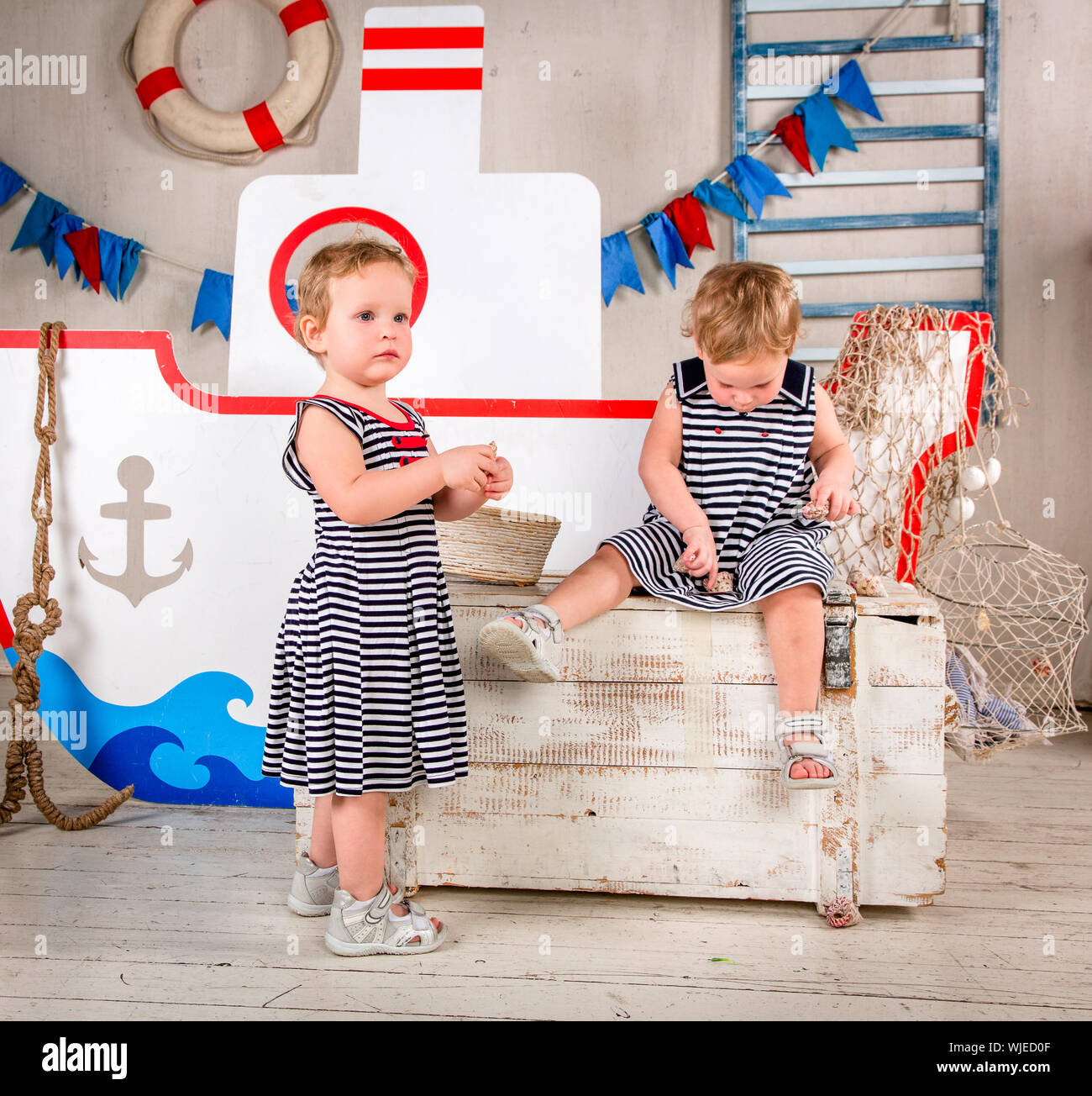 Two little girls play with seashells, sea theme. Stock Photo