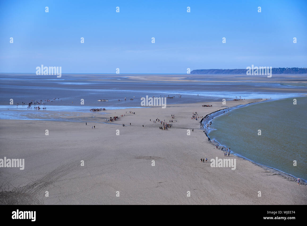 Pilgrims walking across to Mont St. Michel during low tide. Stock Photo