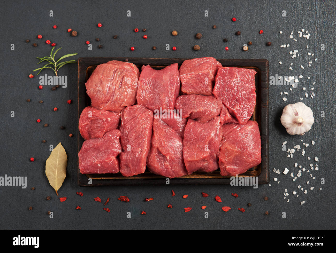 Tasty raw veal or beef meat with spices on the dark background.Pieces of red meat.Flat lay , horizontal orientation. Stock Photo