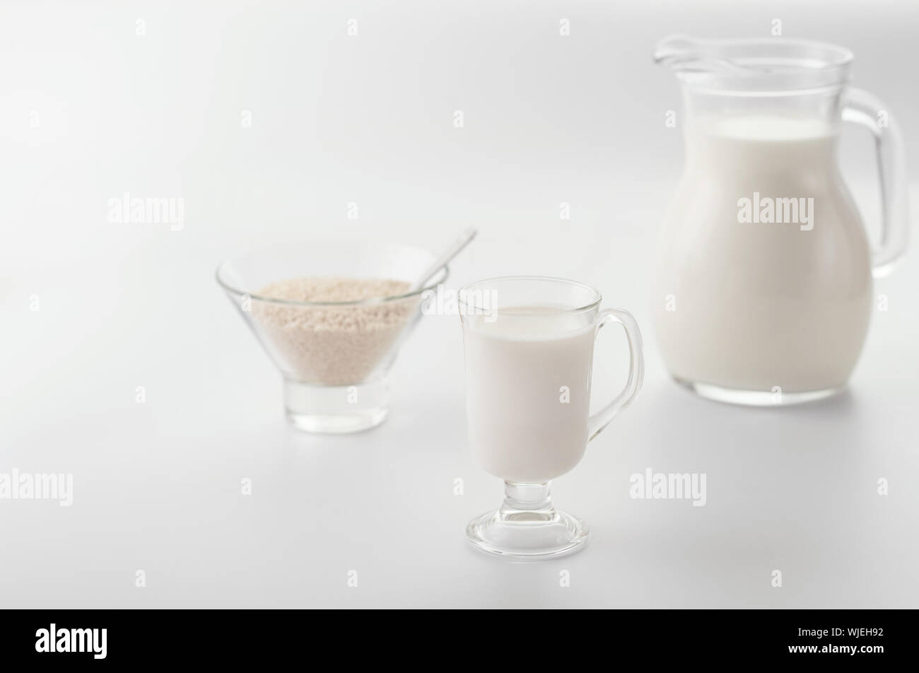 Homemade non diary sesame milk in  glass cup  and in pitcher on light  background. Selective focus. Raw food diet. Vegan concept.Image with copy space. Stock Photo