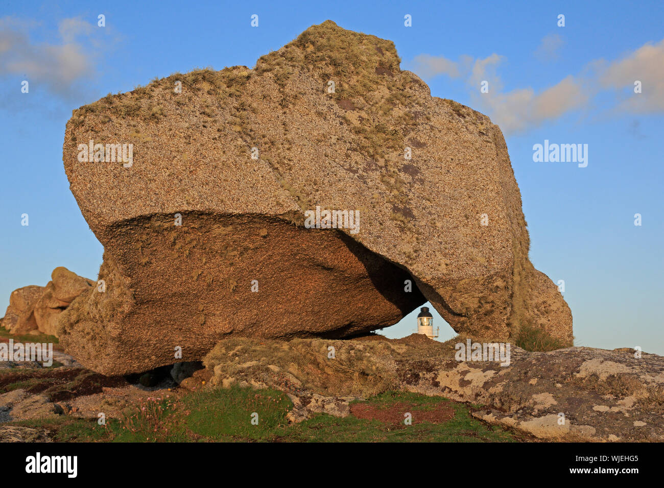 Granite blocks on Penninis Head St Mary's Scilly showing the Lighthouse Stock Photo