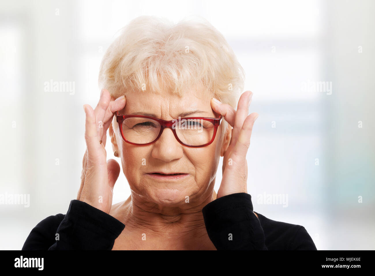 An old woman is eye glasses is having a headache. Isolated on white
