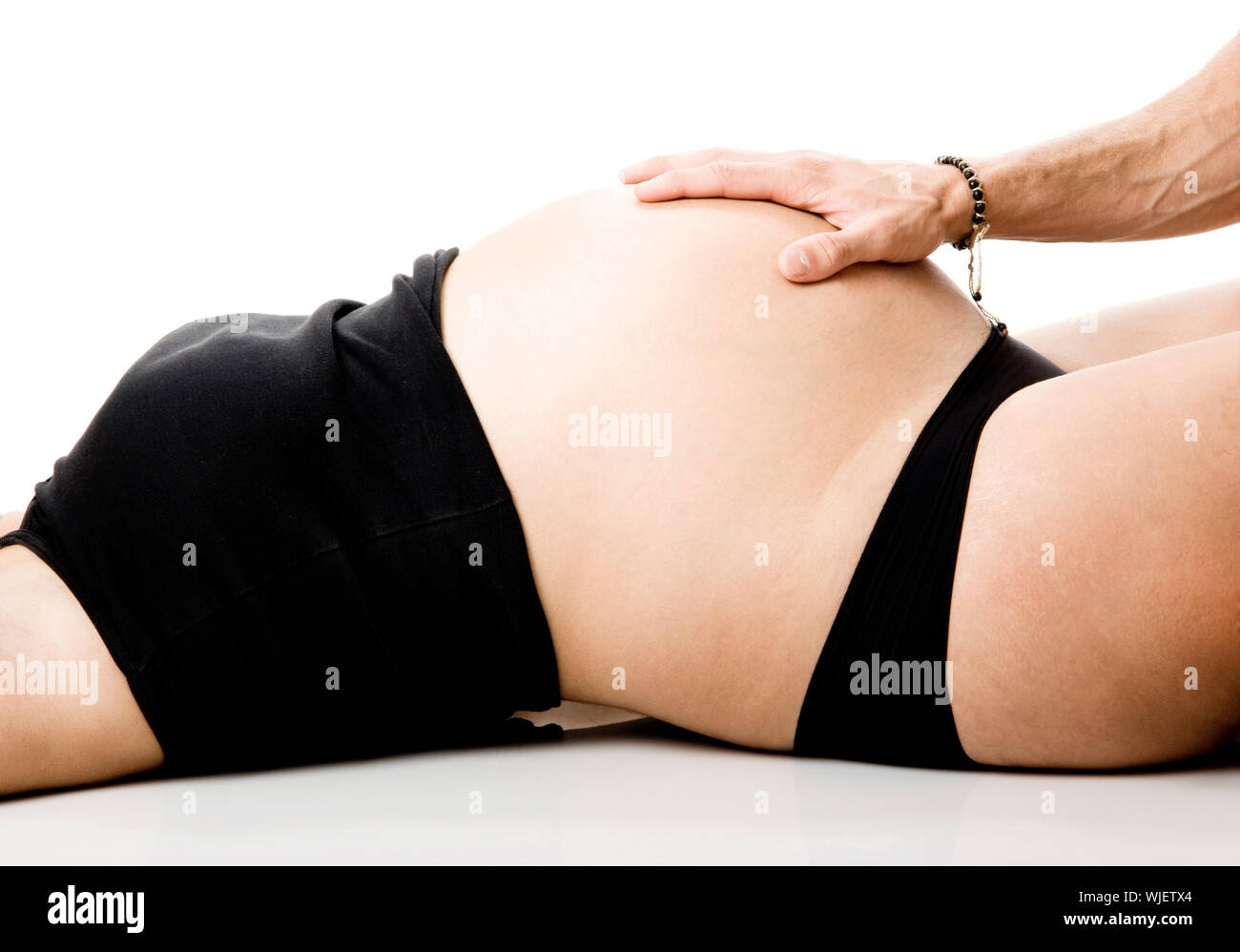 Man hand touch the tummy of a nine months pregnant woman Stock Photo