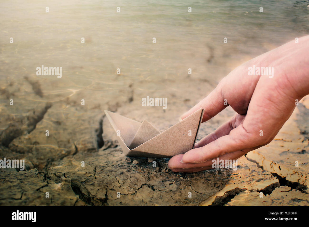 Close-up Of Hand With Paper Boat At Beach Stock Photo