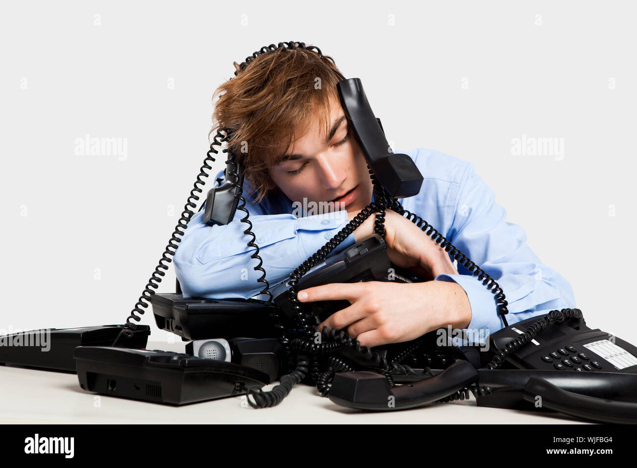 Exhausted man sitting with a bunch of phones over him Stock Photo - Alamy