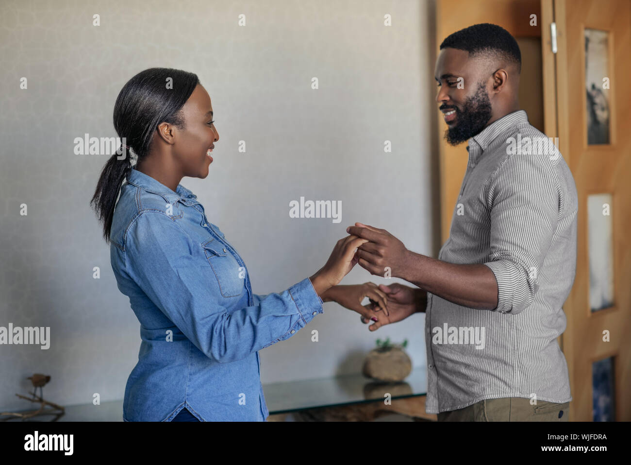 Smiling young African American couple dancing in their living room ...