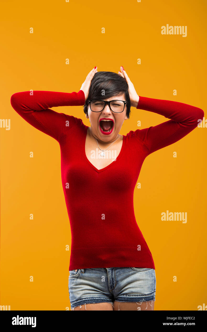 Nerd girl angry with something, aganist a yellow background Stock Photo