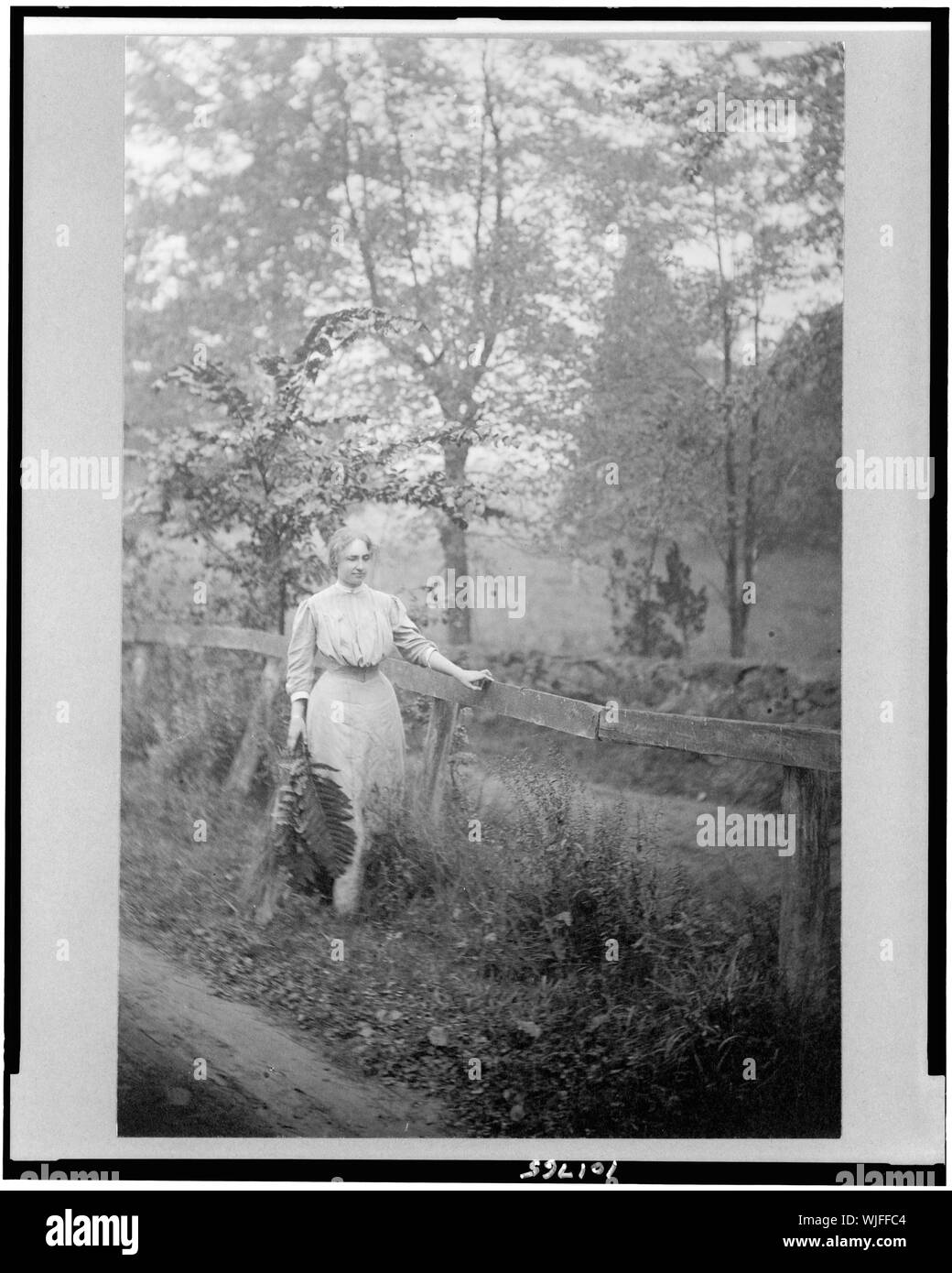 Helen Keller, full-length portrait, standing by fence, holding palm ...