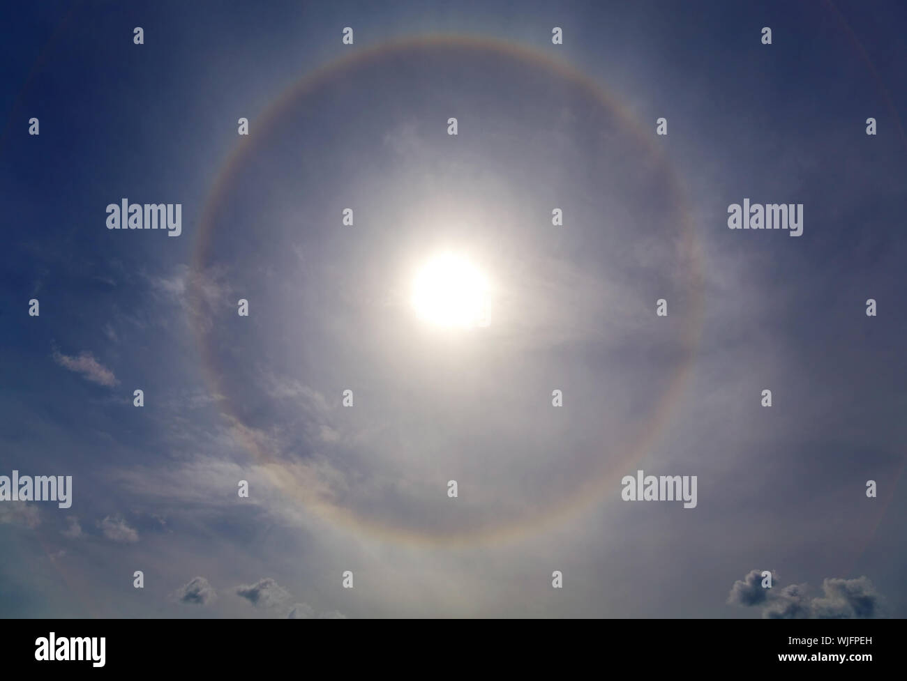 Circles halo in the blue cloudy sky around of the sun Stock Photo