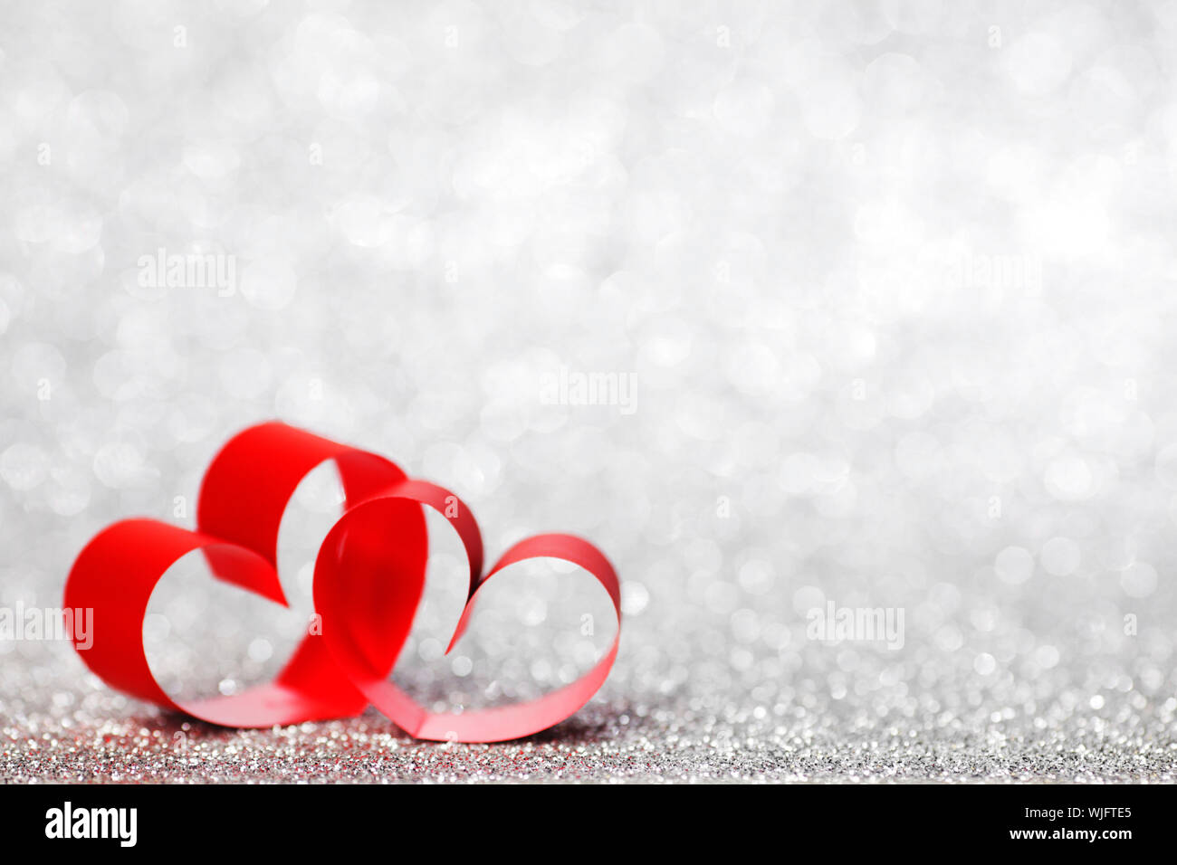 Red ribbon hearts on shiny glitter background Stock Photo - Alamy