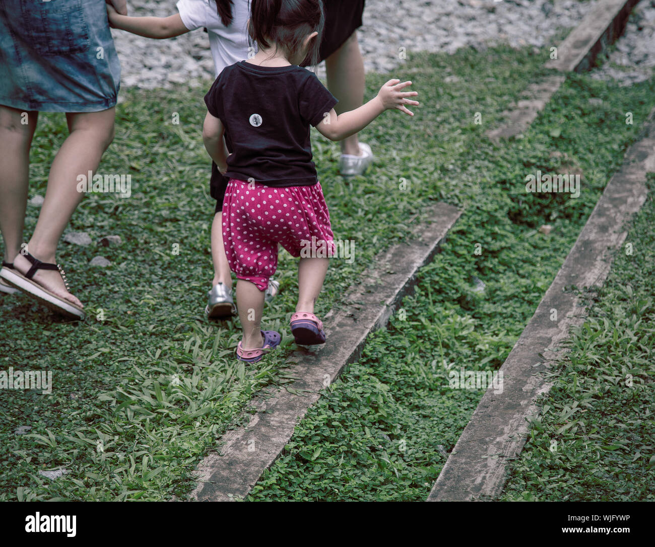 Mother With Daughters Walking On Grassy Field Stock Photo