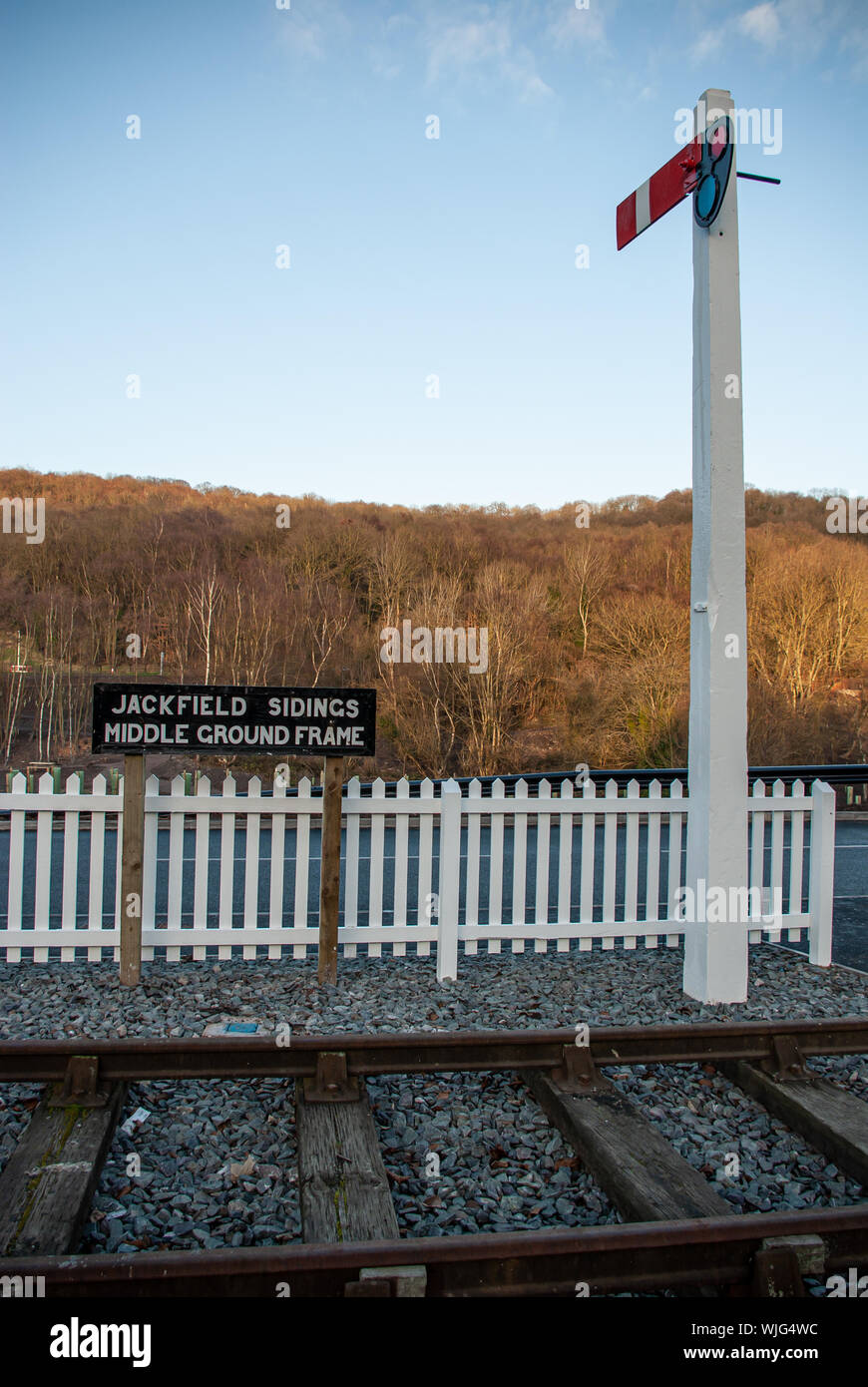 Railway sidings sign next to a railway track with signal post and white wicket fence behind Stock Photo