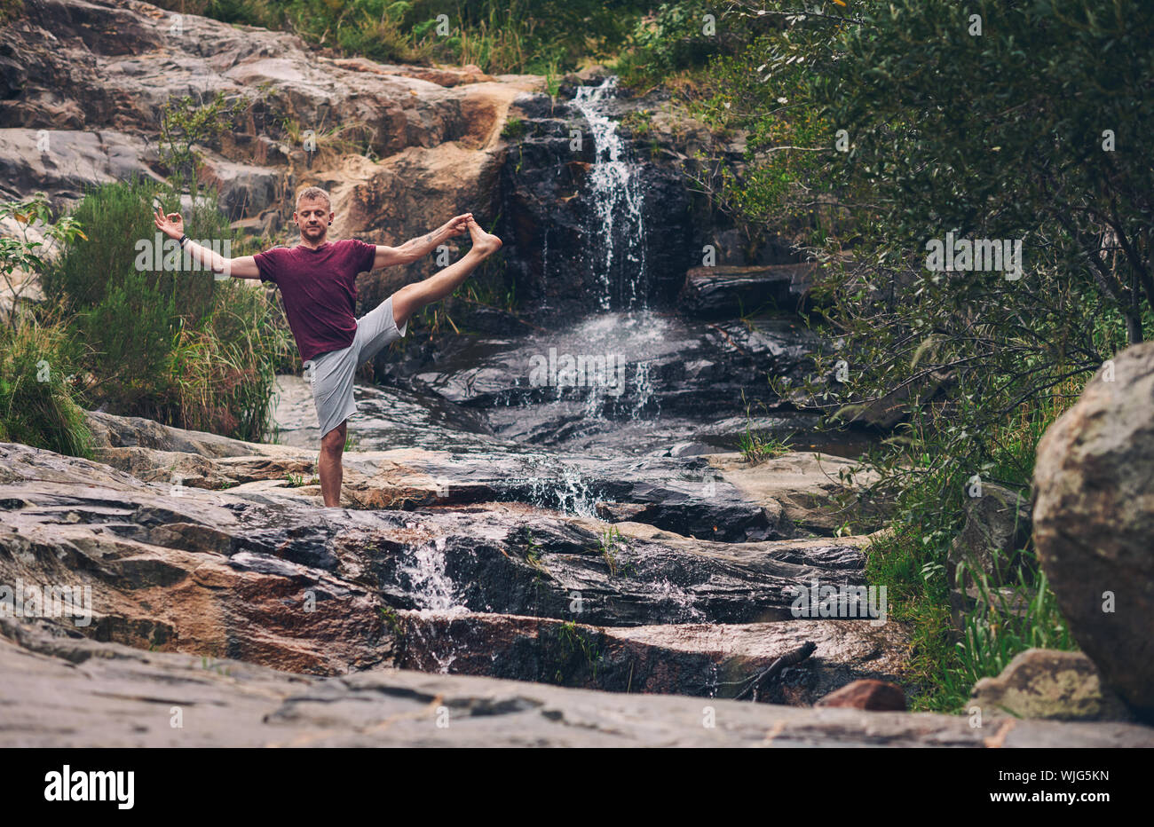 Man doing the extended standing hand to toe pose outdoors Stock Photo