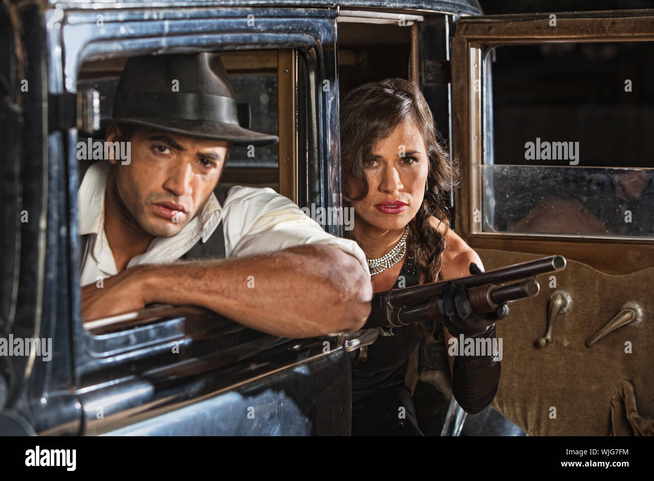 1920s gangster duo in car with shotgun on look out Stock Photo