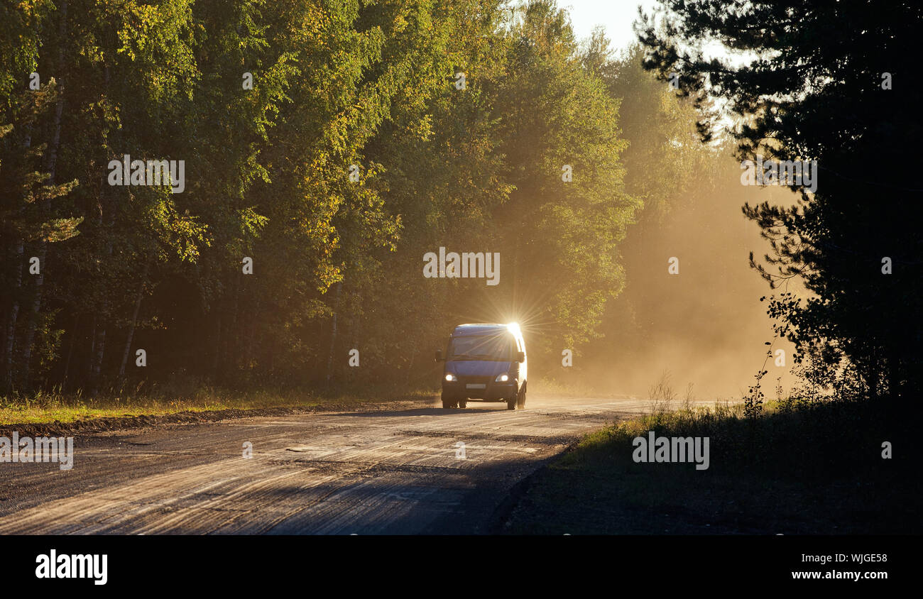 Car on the Road through forest in sunset fog Stock Photo - Alamy