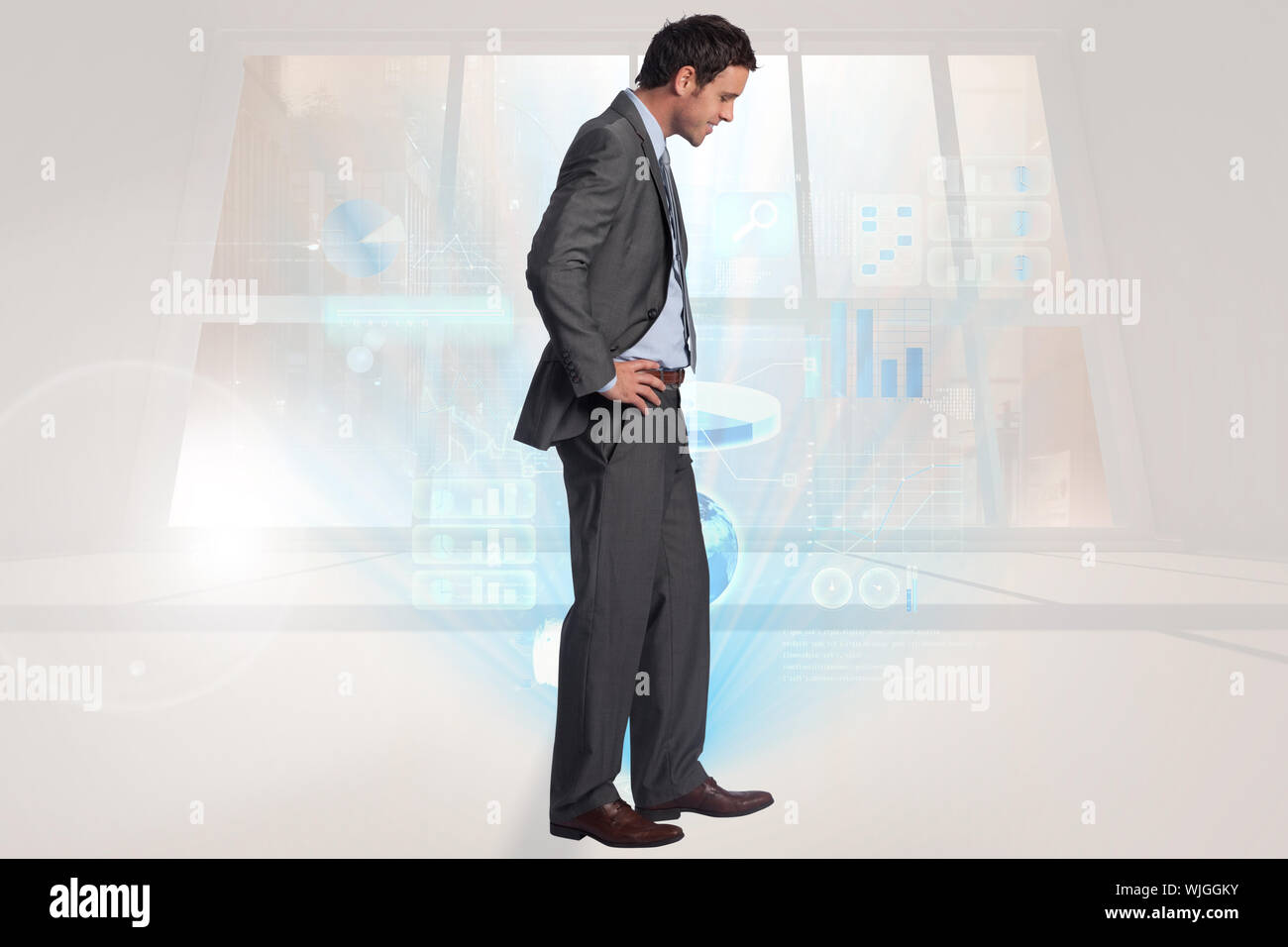 Smiling businessman with hands on hips against airplane flying past ...