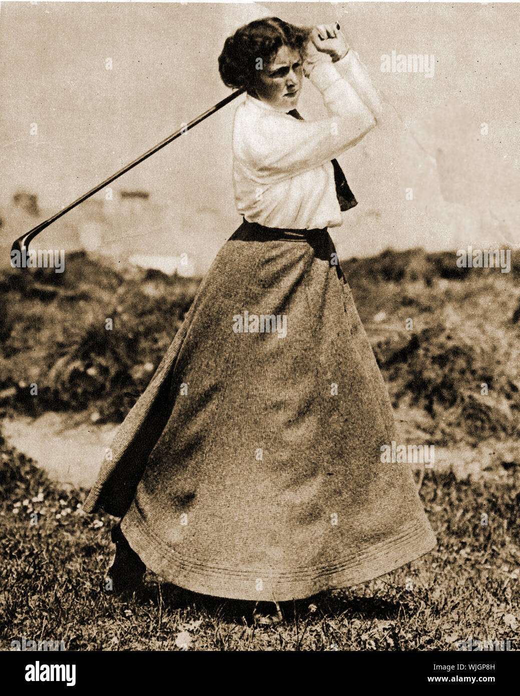 Women playing traditional sports in 1911. A female playing golf in a   a formal long skirt Stock Photo