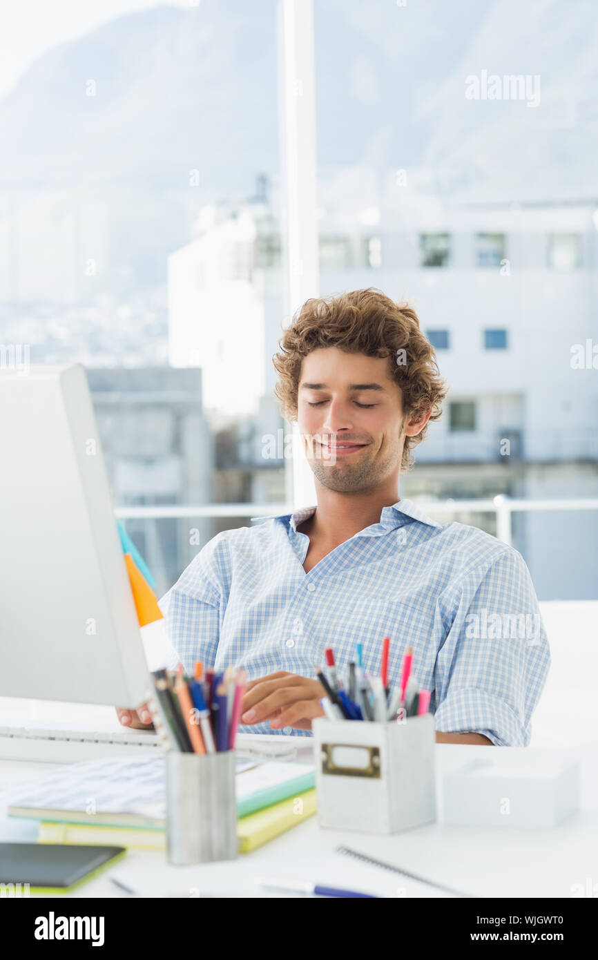 Concentrated casual young business man using computer in a bright ...