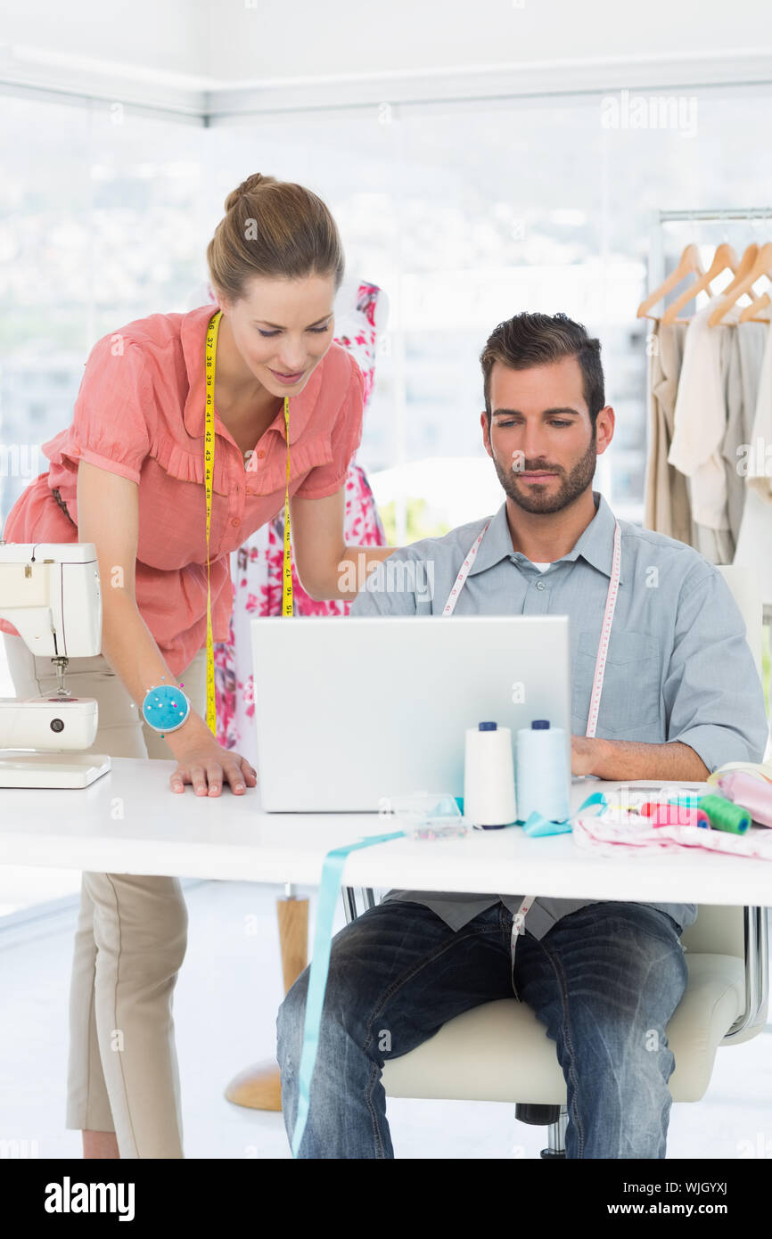 Male and female fashion designers using laptop in a bright studio Stock ...