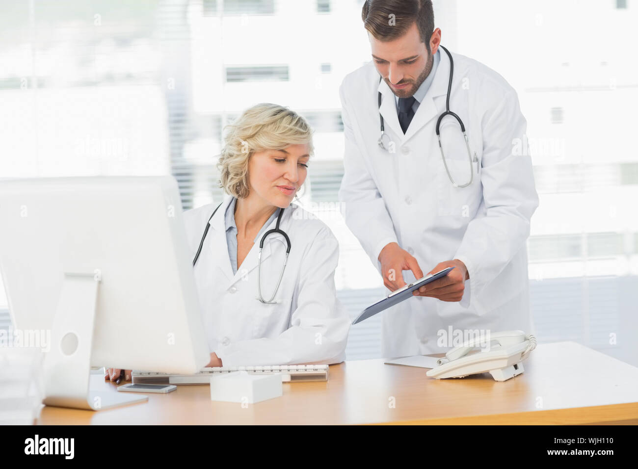 Two doctors using digital tablet by computer at medical office Stock Photo