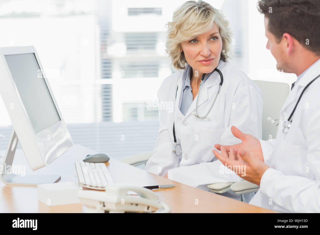 Two concentrated doctors discussing something by computer at medical office Stock Photo