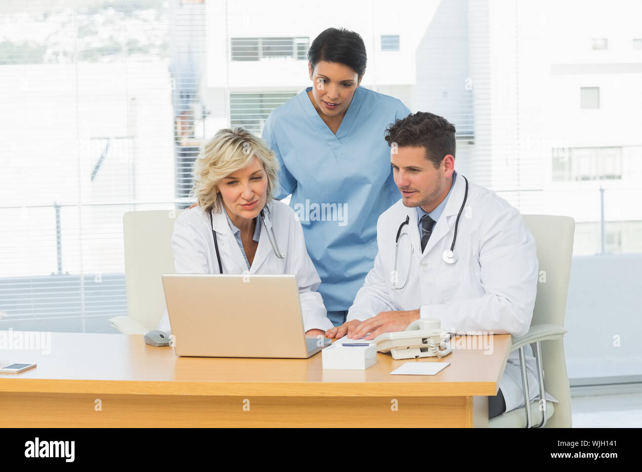 Three concentrated doctors using laptop together at the medical office Stock Photo