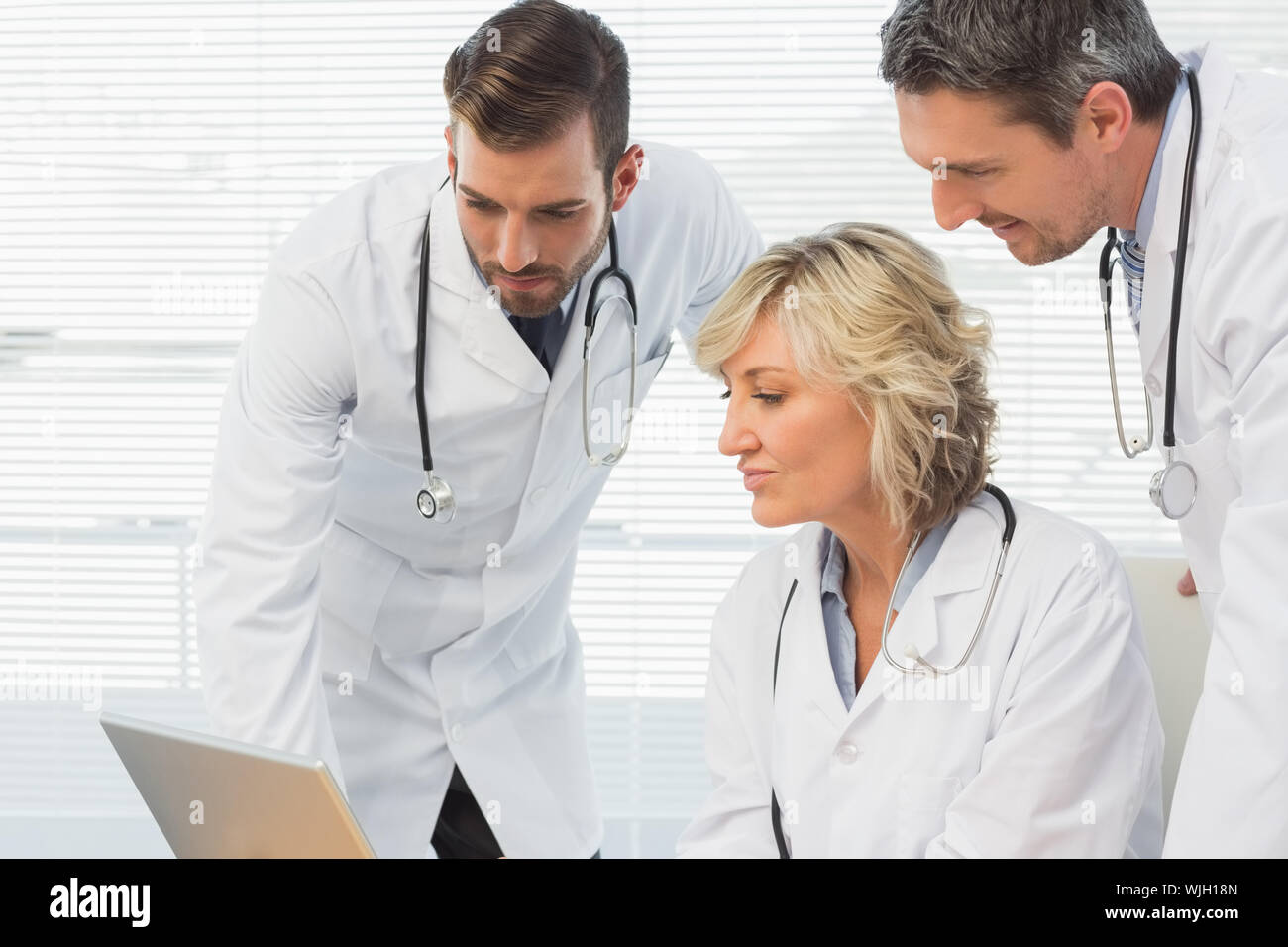 Three concentrated doctors using laptop together at the medical office Stock Photo