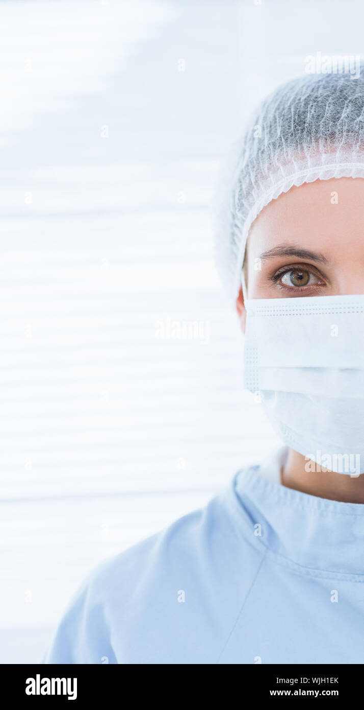Close-up portrait of a female surgeon wearing surgical cap and mask in ...