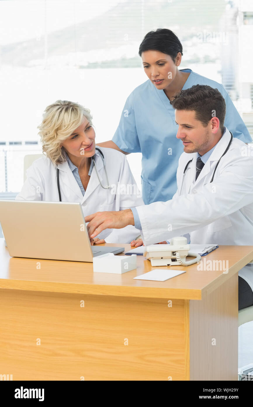 Three concentrated doctors using laptop together at the medical office Stock Photo