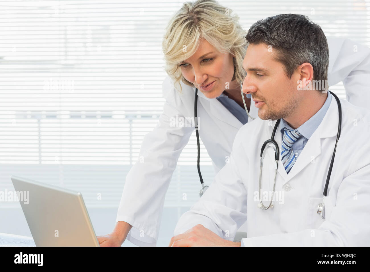 Two concentrated doctors using laptop together at the medical office Stock Photo