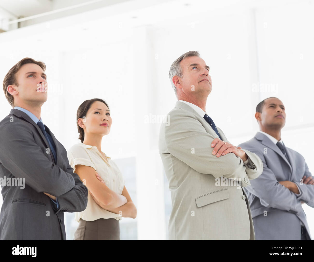 Serious business team with arms crossed looking up in the office Stock ...