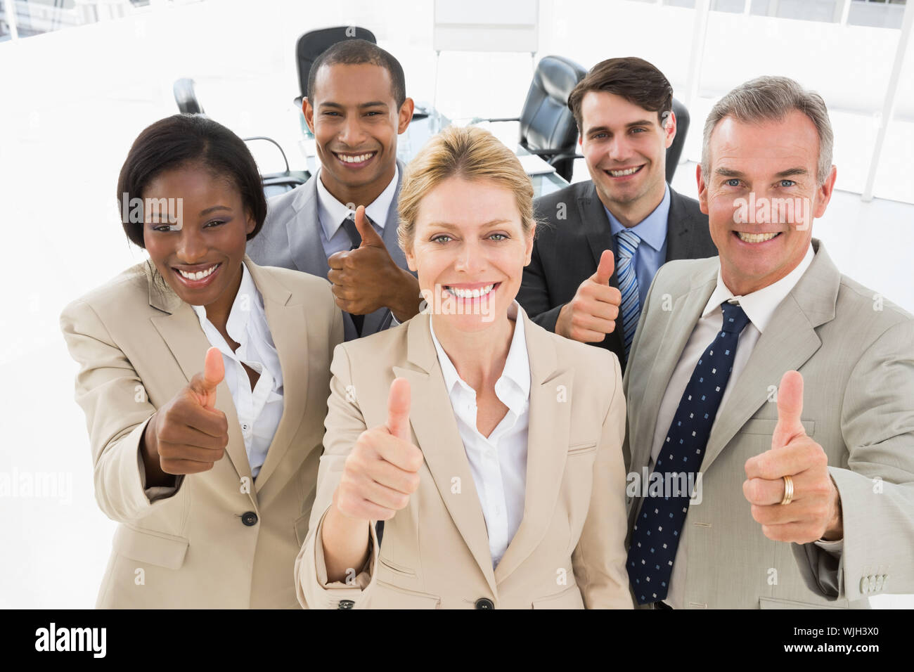 Diverse close business team smiling up at camera giving thumbs up in ...