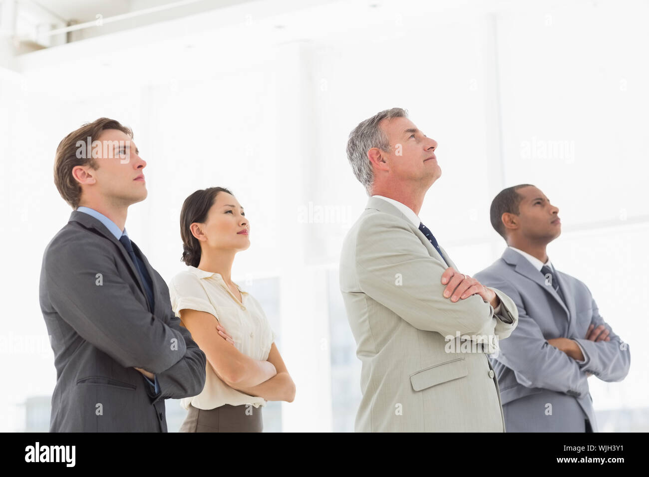 Serious business team with arms folded looking up in the office Stock ...