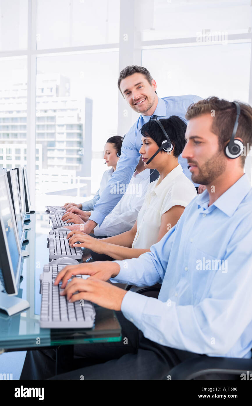 Side view of manager and executives with headsets using computers in