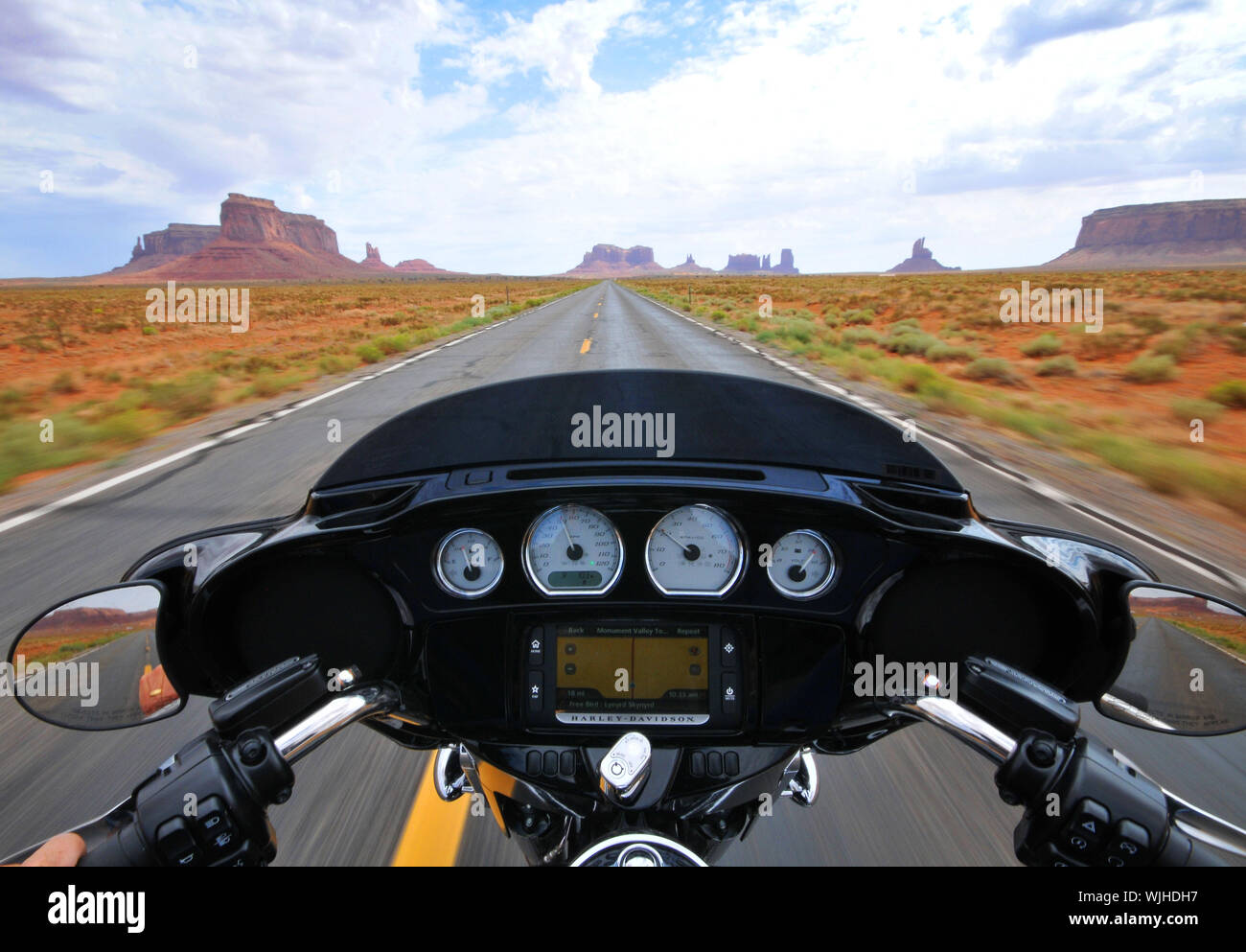 A Harley-Davidson rides along the iconic U.S163 Scenic Route, Monument Valley on the Utah, Arizona border USA listening to Freebird, Lynyrd Skynyrd. Stock Photo