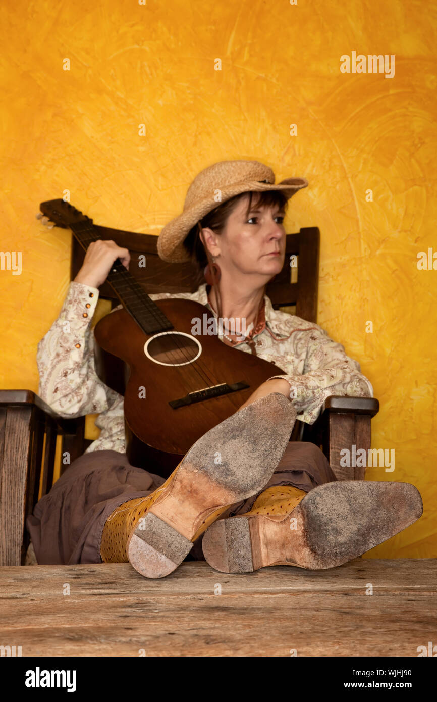 Pretty Western Woman In Antique Rocking Chair With Guitar Stock