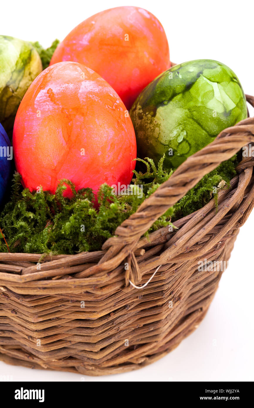 Rustic wicker basket of brightly coloured hand-painted traditional Easter Eggs with a marbled pattern nestling in a bed of green moss, high angle view Stock Photo