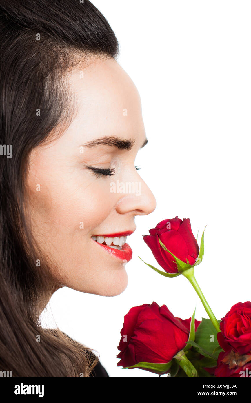 Close-up portrait of a beautiful woman smiling and smelling a rose ...