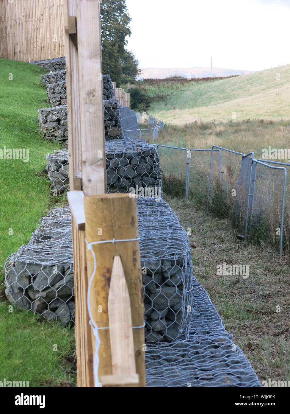 A retaining wall constructed from gabions, or wire mesh cages filled