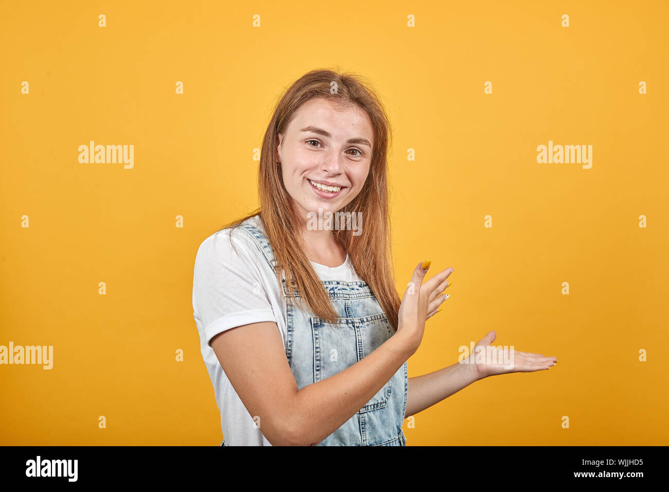 Young woman wearing white t-shirt, over orange background shows emotions Stock Photo