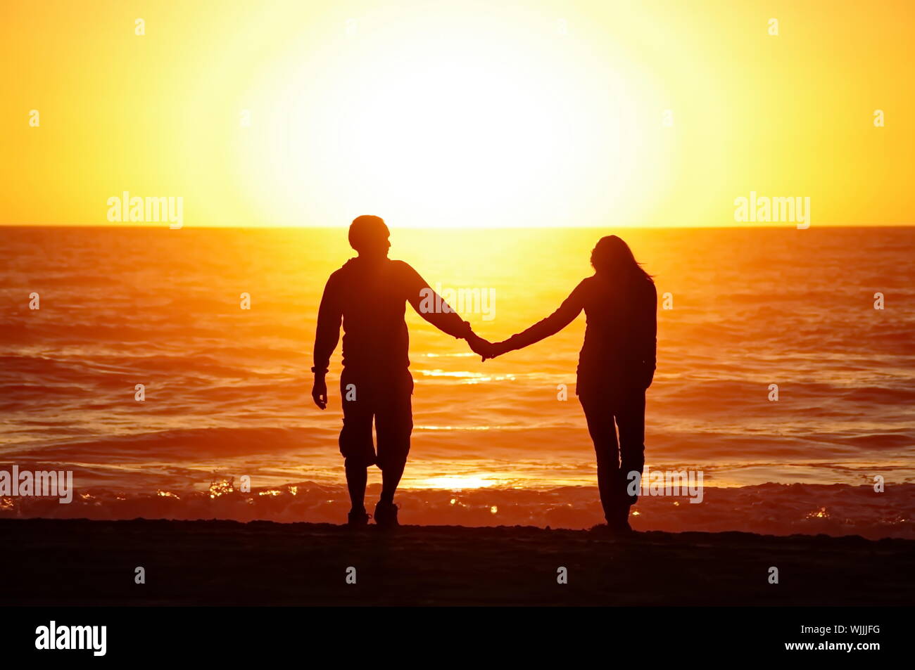 Man and woman holding hands on beach hi-res stock photography and ...