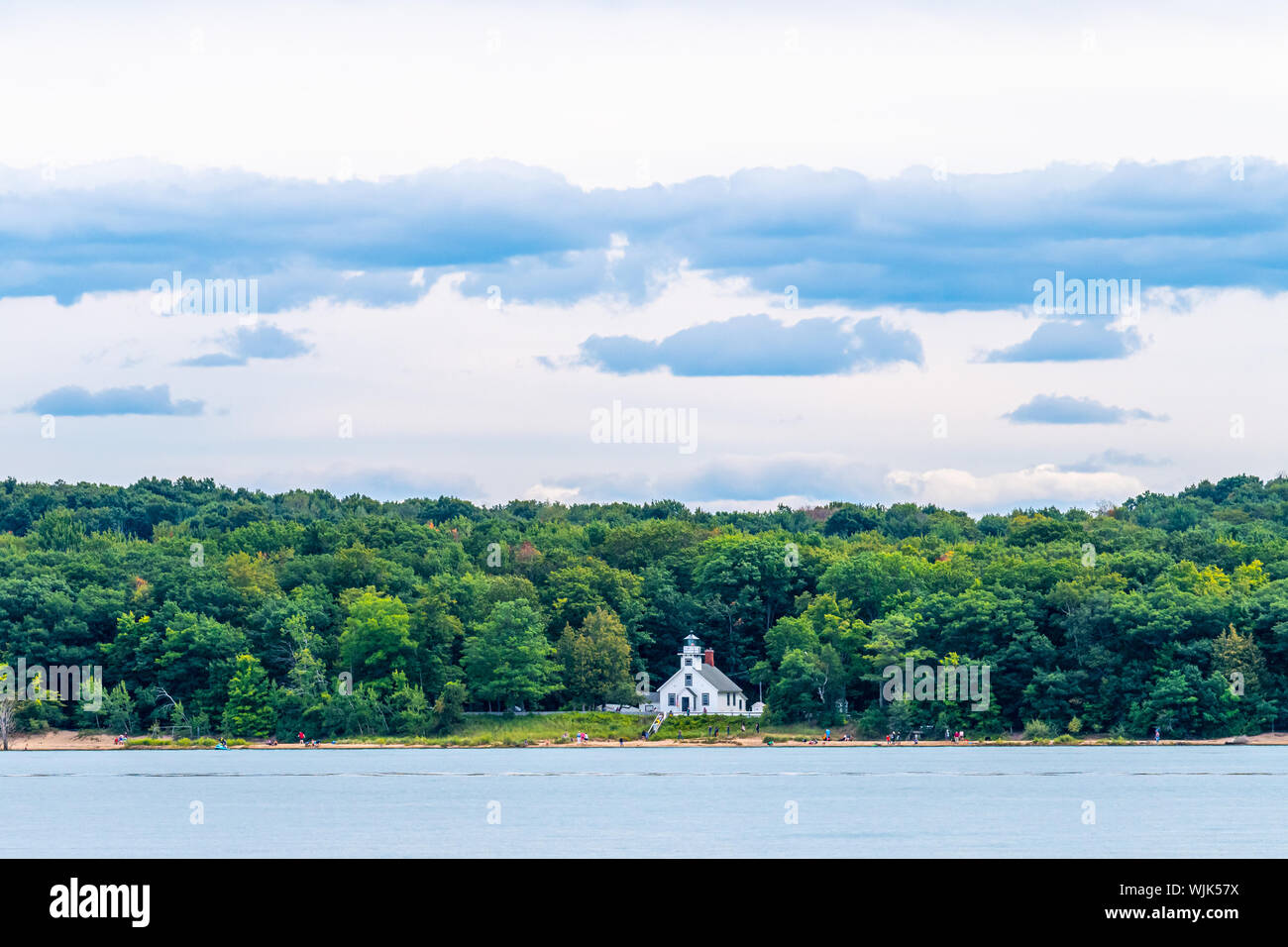 People walk on the beach in front of the Old Mission Point Lighthouse on Old Mission Peninsula near Traverse City, Michigan, as viewed from the water. Stock Photo