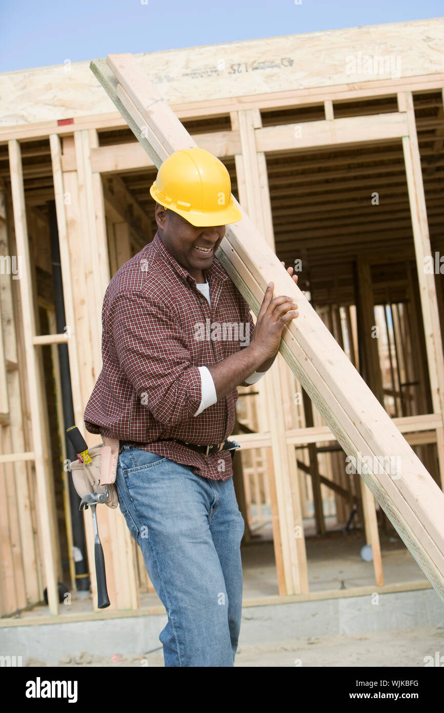 Construction worker carrying wooden plank Stock Photo - Alamy