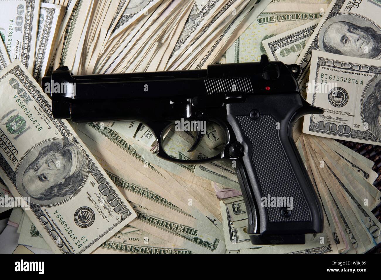 Dollar notes and gun, black pistol, mafia inspiration Stock Photo - Alamy